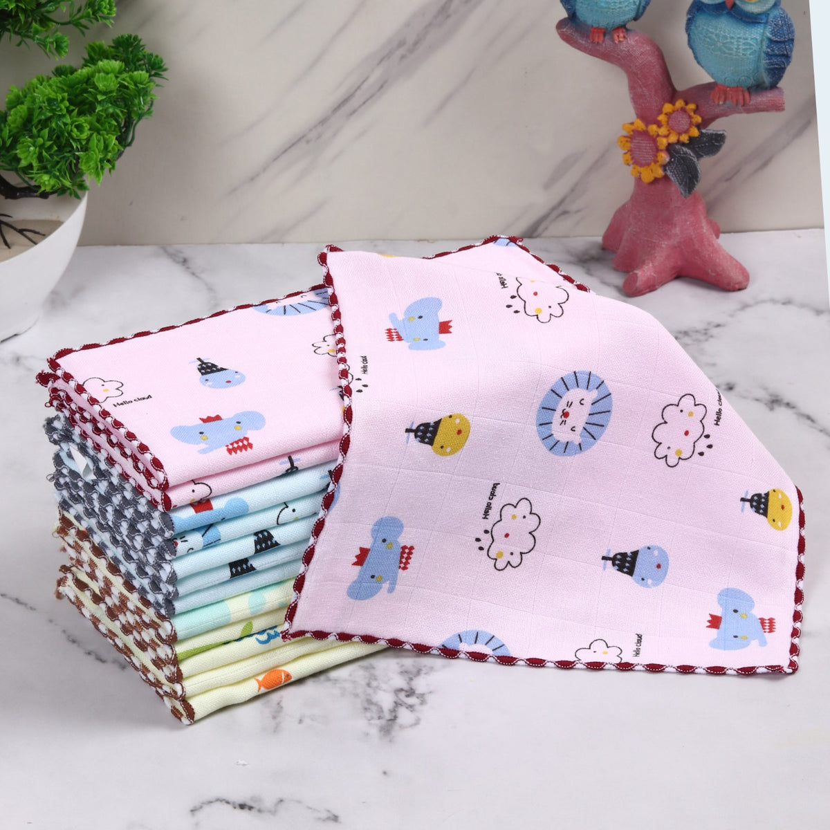 Printed cotton baby face towels stacked with a pink towel displayed